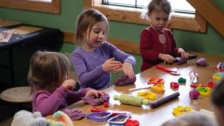 Three children engaged in hands on play with modeling tools at Schweitzer's summer camp for kids