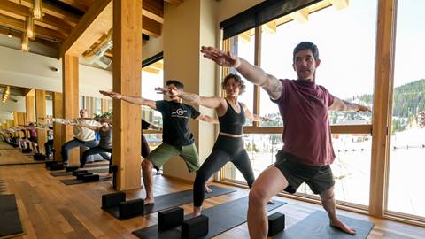 Group yoga class in session at Cambium Spa at Schweitzer, led by a certified instructor in the sunlit spa room as part of seasonal day spa treatments