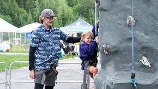 An employee showing a kid how to rock climb at Schweitzer