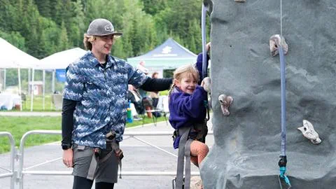 An employee showing a kid how to rock climb at Schweitzer