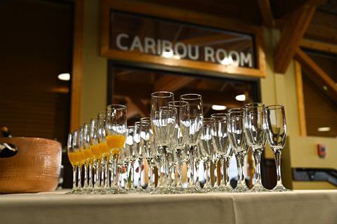 Rows of champagne and mimosa glasses are arranged on a draped table in front of the Caribou Room at Schweitzer