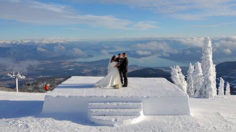A bride and groom stand atop a platform carved from snow for a winter wedding ceremony at Schweitzer.