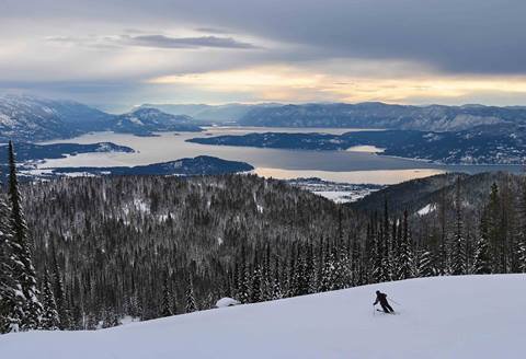 skier going down slopes with lake pend oreille in the background