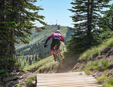 Biker catching air on a jump while riding a full suspension mountain bike at Schweitzer