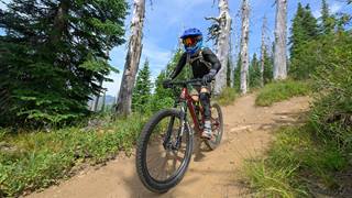 Rider in full gear descending a dirt trail at Schweitzer on a full suspension mountain bike rental 