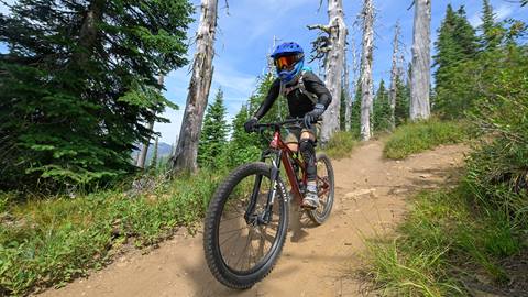 Rider in full gear descending a dirt trail at Schweitzer on a full suspension mountain bike rental 