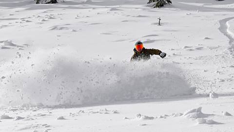 snowboarder on performance snowboard rentals at schweitzer riding through deep powder snow