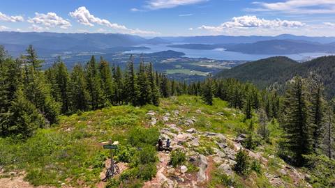 drone view of two people sitting down and soaking up the view of Lake Pend Oreille