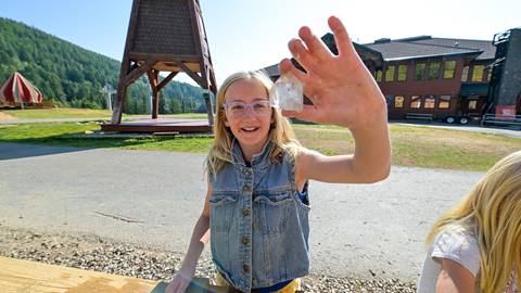 child holding a gemstone with a smile at Schweitzer's mining sluice, included with the ultimate fun pass